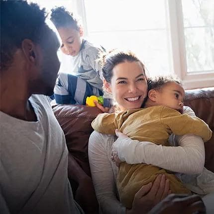 Woman holding child with husband and other child in background